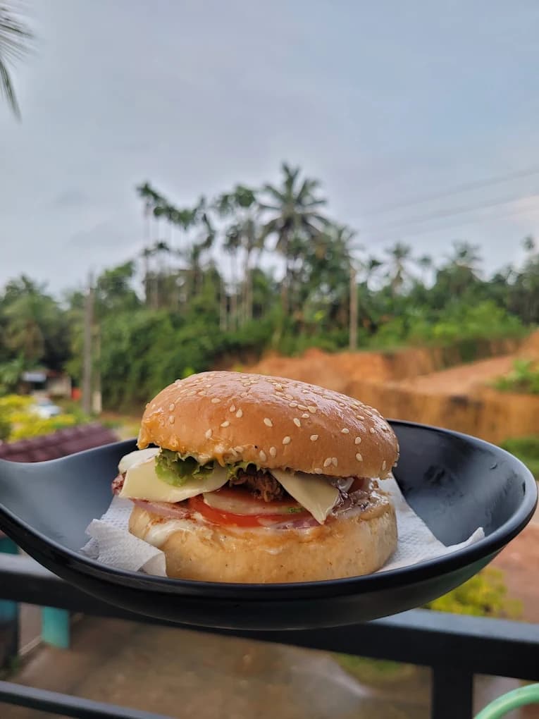 Signature chicken cheese burger at River Queen lakeside cafe in Shantimogaru